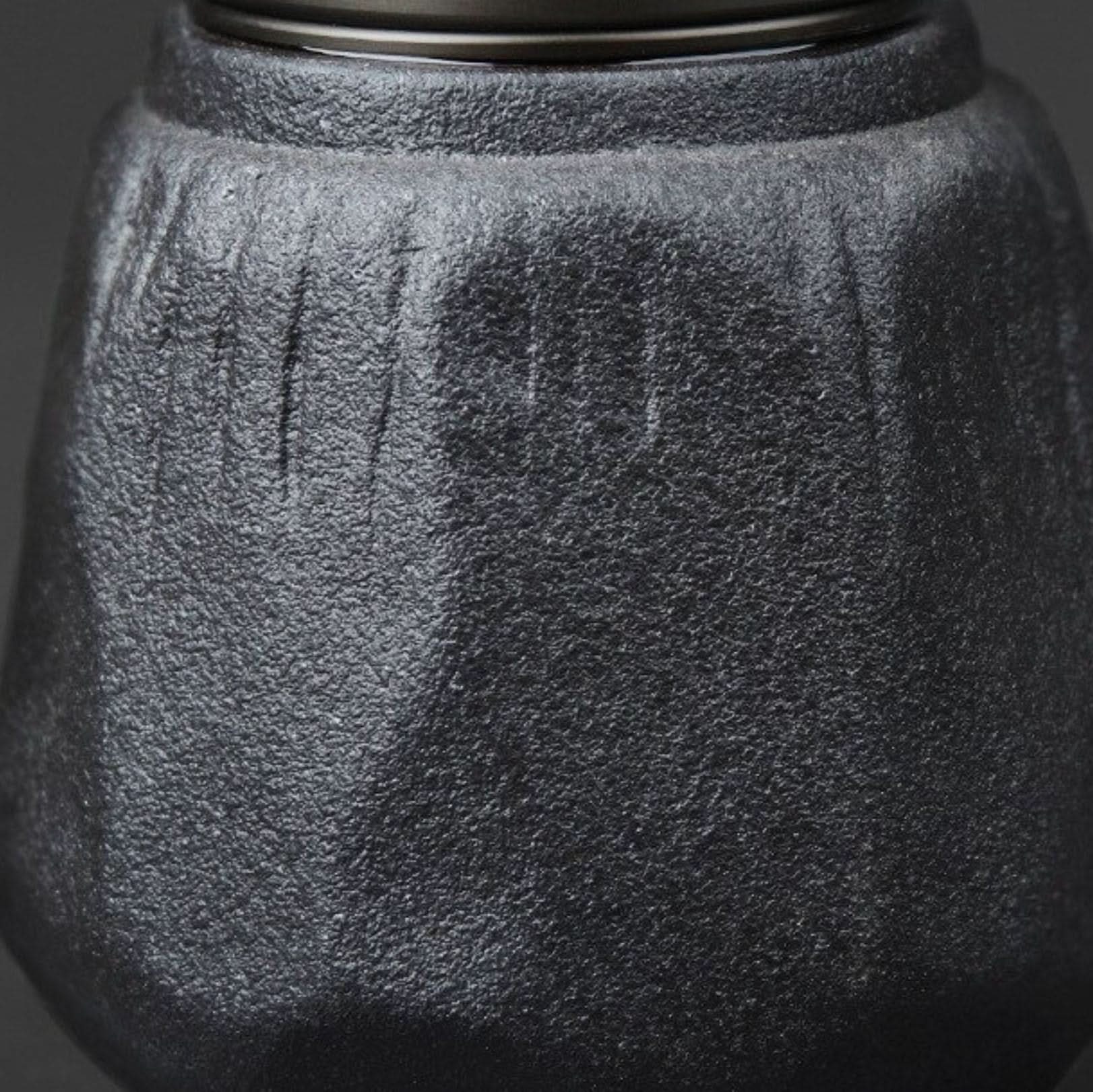 Textured black stoneware sealed tea can with metallic rim detail.